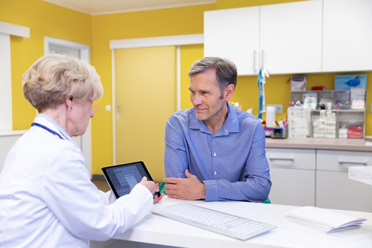 Ärztin und Patient sehen gemeinsam auf ein Tablet
