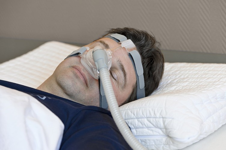 Schlafender Mann mit einem Gerät zur nächtlichen Überdruckatmung
