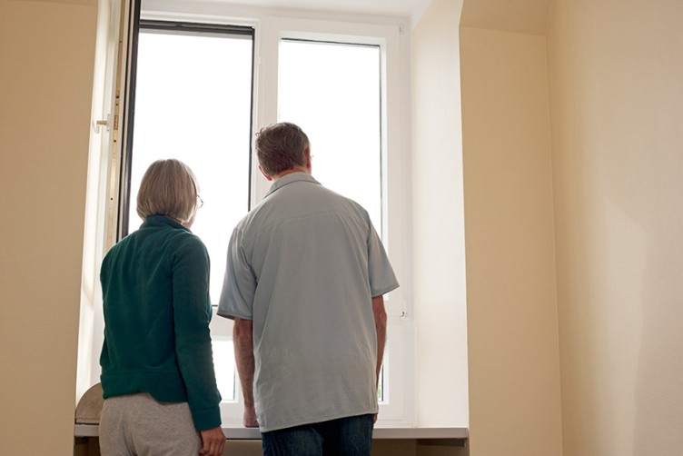 Zwei Menschen sehen aus dem Fenster eines Pflegeheims