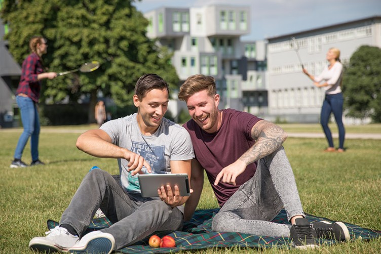 Zwei Jugendliche auf einer Wiese mit Tablet