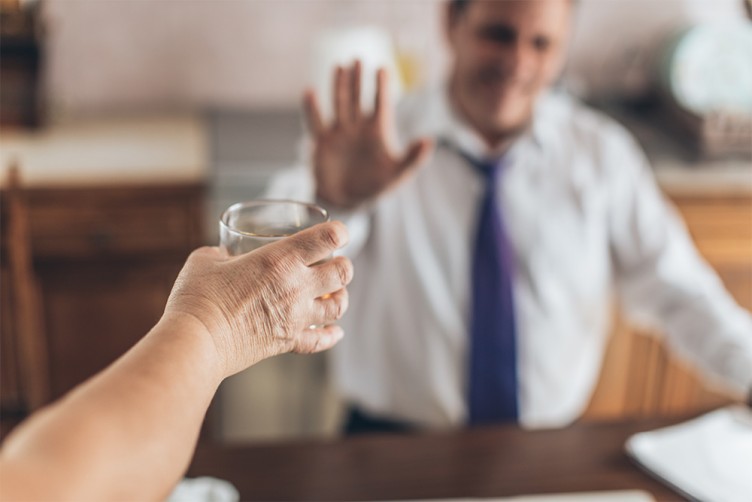 Einem Mann wird ein Glas Alkohol angeboten, er lehnt ab.