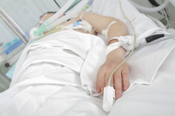 Ein Patient liegt mit einem Beatmungsgerät im Krankenbett