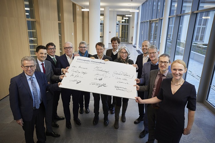 Mehrere Menschen, darunter Gesundheitsminister Karl Lauterbach, stehen um ein Schild mit Unterschriften herum