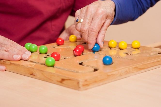 Hände von zwei älteren Menschen spielen ein Geschicklichkeitsspiel