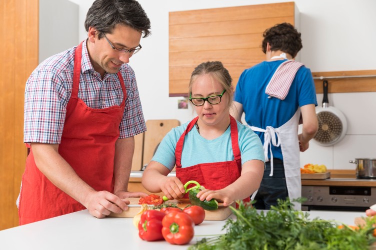 Eine junge Frau mit Down-Syndrom und ein Mann beim gemeinsamen Kochen