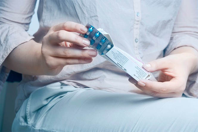 Eine junge Frau öffnet eine Packung mit Tabletten