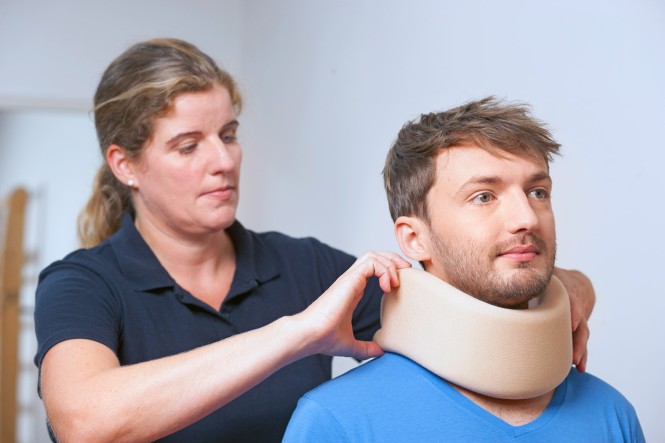 Eine Frau legt einem Mann eine Hals-Nackenkrause an