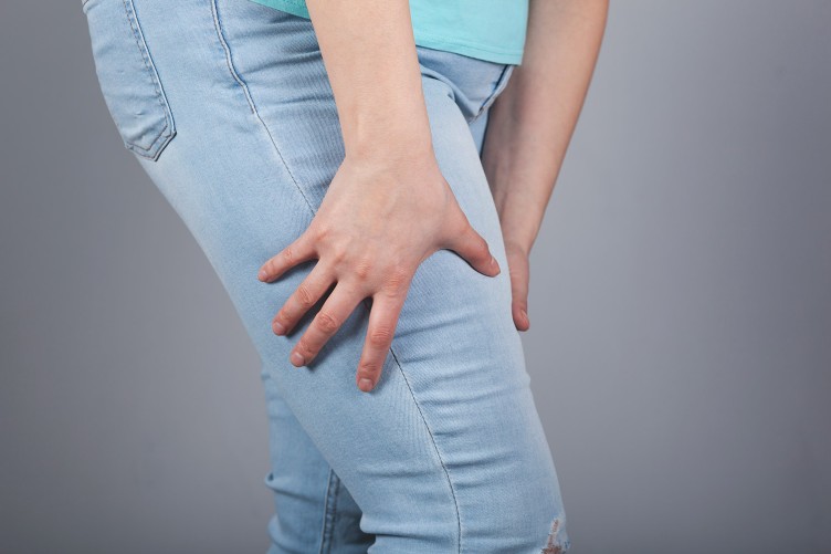Eine Frau mit Lipödem umfasst ihr Bein