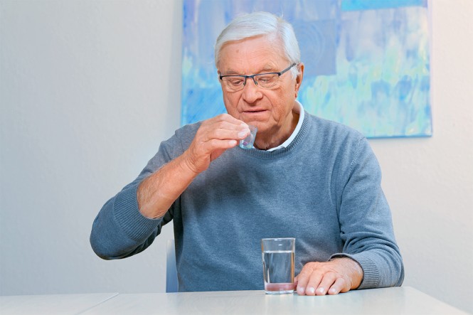 Ein älterer Mann nimmt eine Tablette ein
