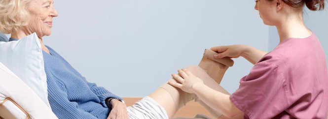 Eine Pflegekraft versorgt eine ältere Frau in einem Pflegebett