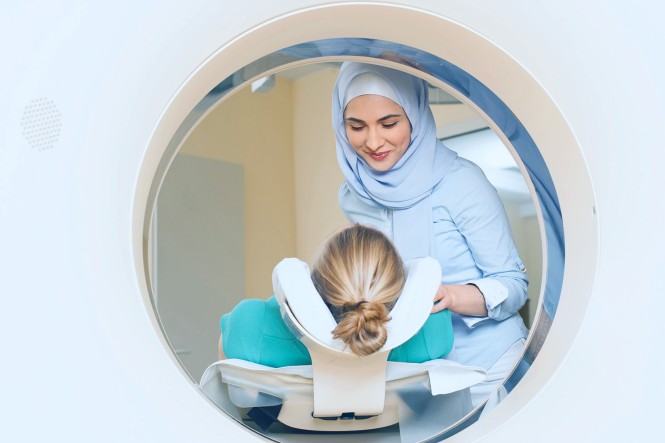 Eine MTA bereitet eine Patientin zur CT-Untersuchung vor